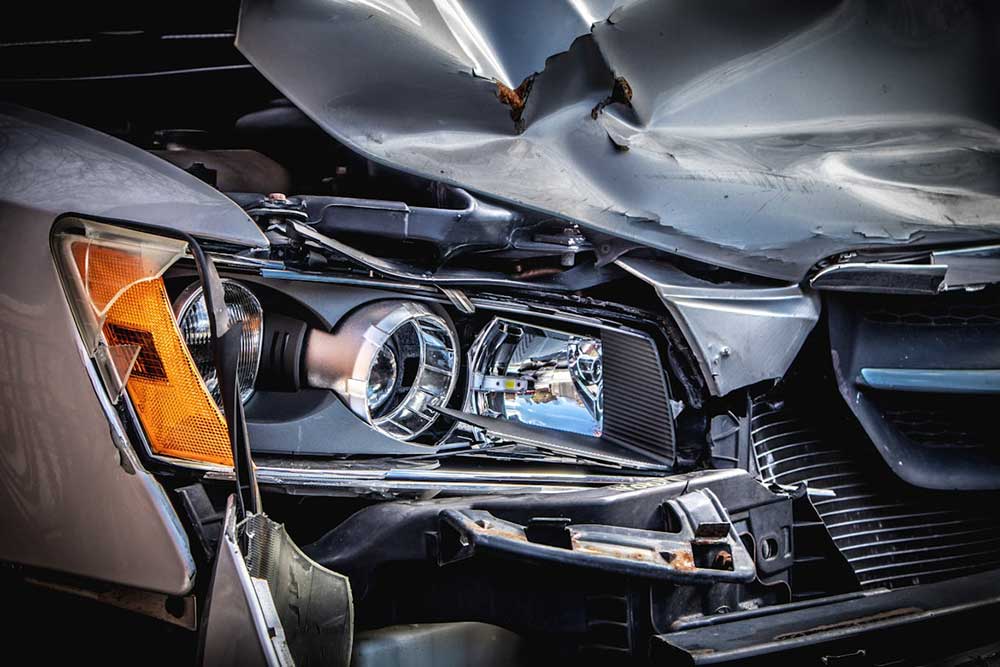The close up of a heavily damaged front end of a grey car